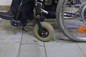  Wheel of a wheelchair at the edge of a kerb stone 